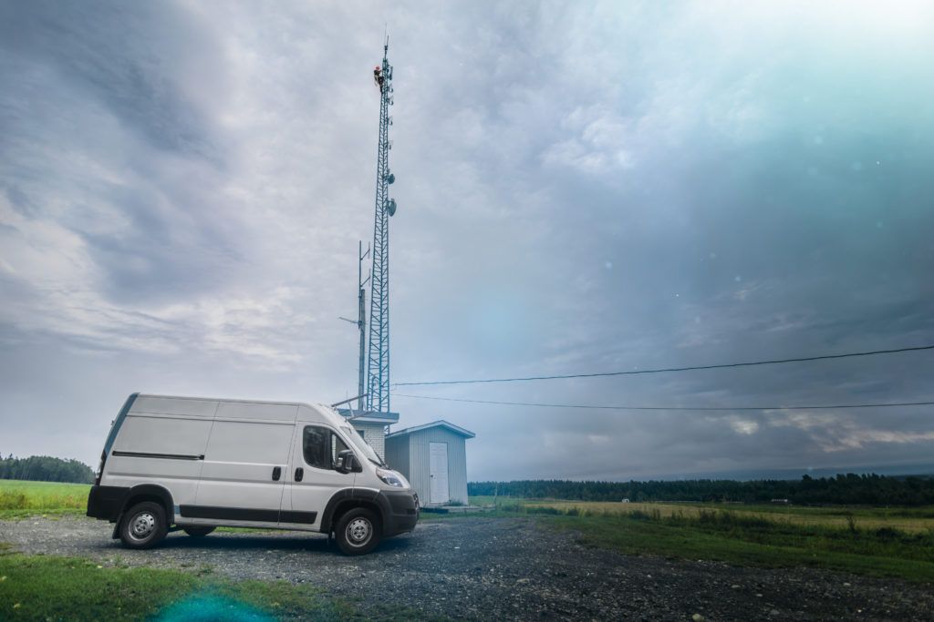 Technician climbing on top of telecom tower for maintenance in the field.